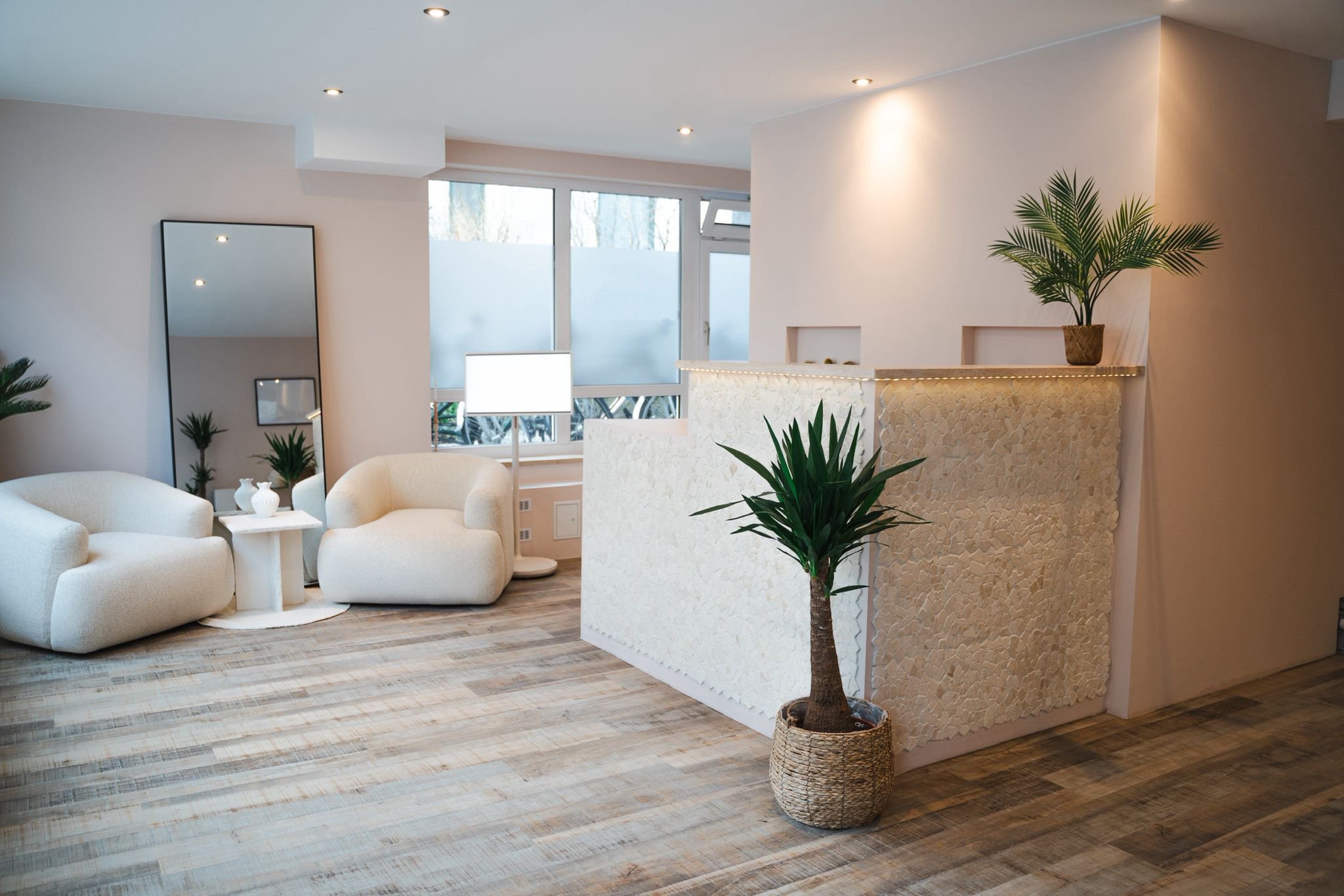 Innenbereich des Sueños Beauté Studios mit Empfangstheke, Lounge-Sitzgelegenheiten und hellen, neutralen Einrichtungsdetails