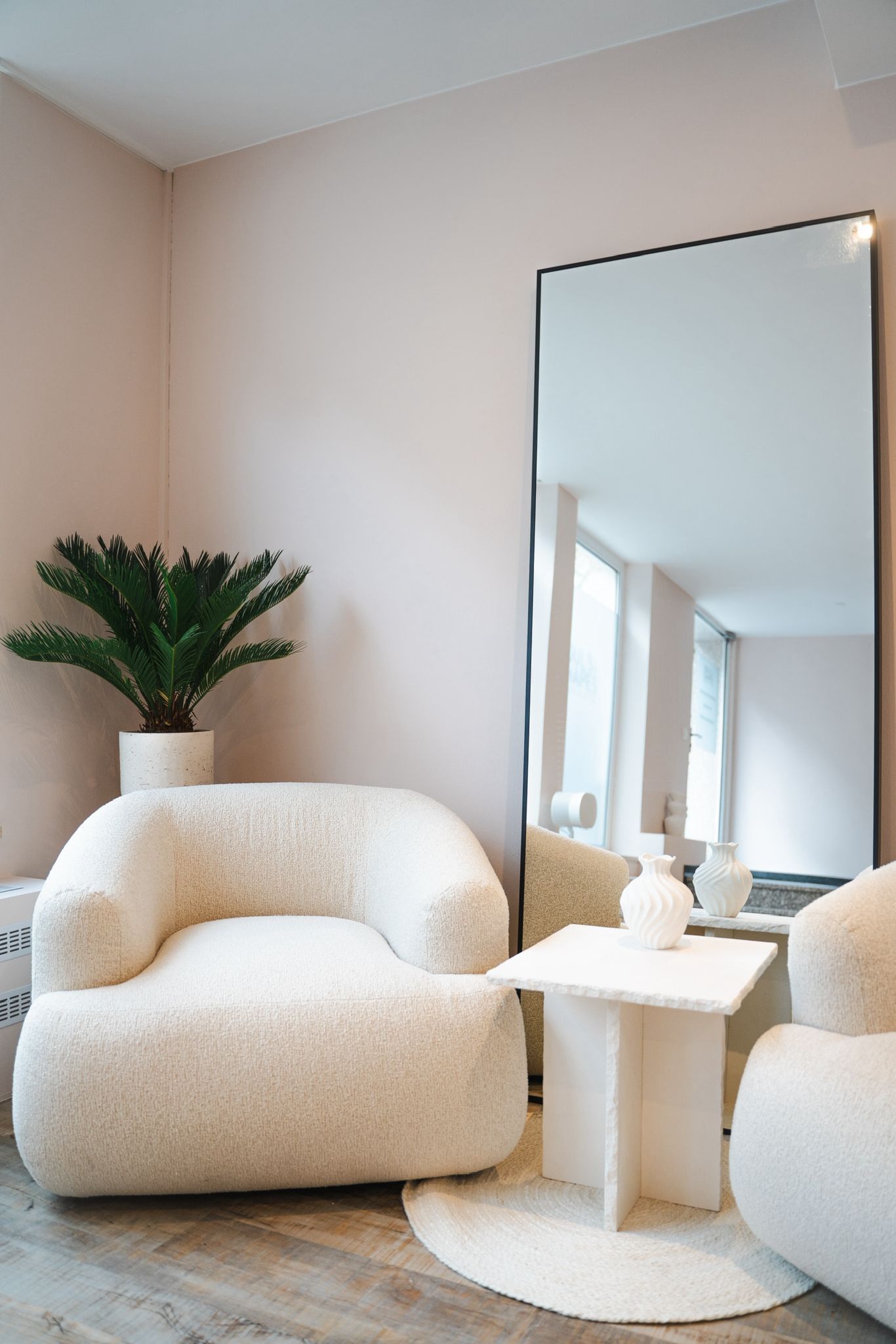 Empfangsbereich des Sueños Beauté Studios mit eleganten Stühlen, Spiegel und hellen, neutralen Einrichtungsdetails